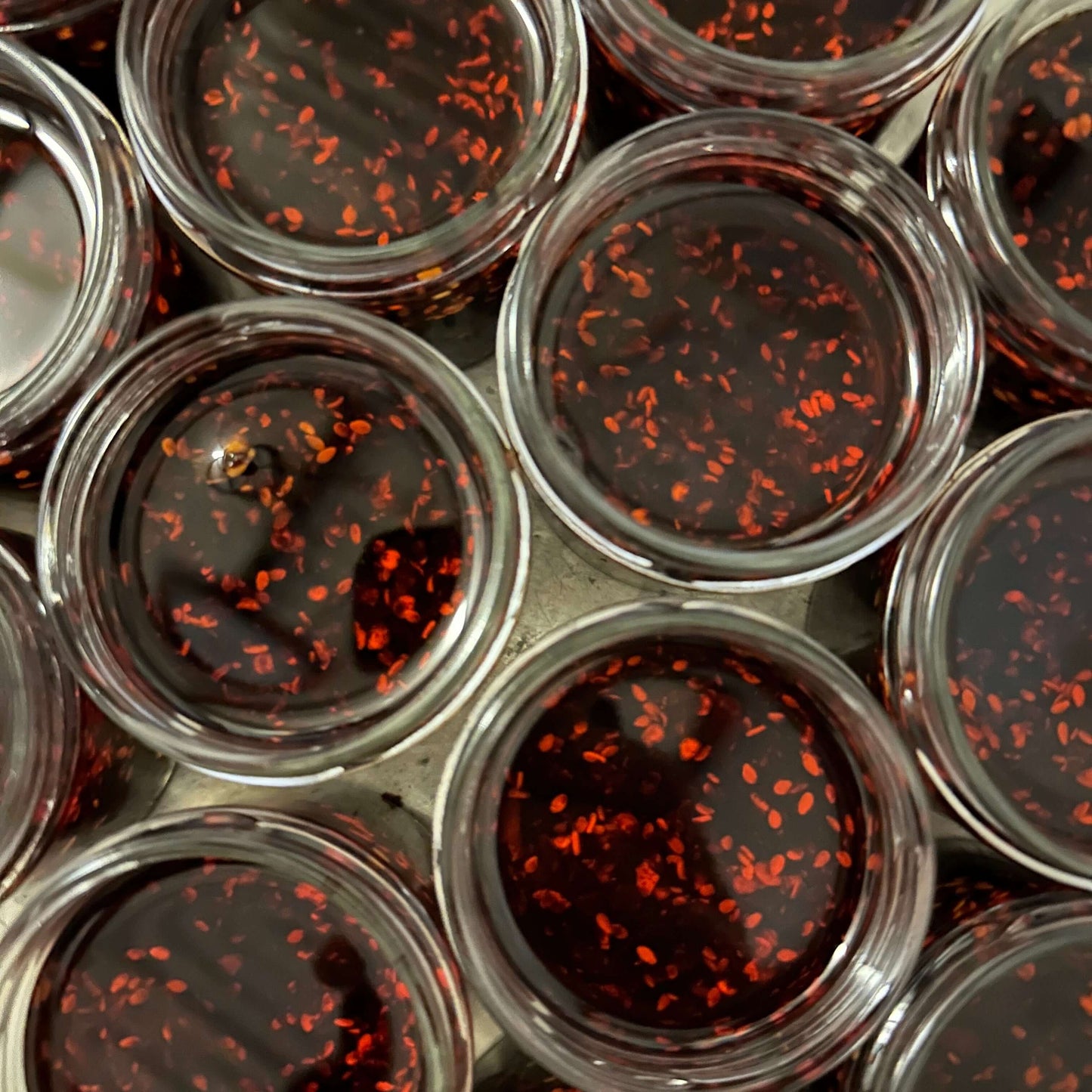 Jars of spicy chili oil filled with red chili flakes, showcasing a vibrant texture and rich color.